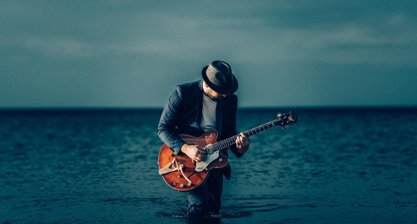 Ander Zubillaga inclinado sobre la guitarra, tocando dentro del mar